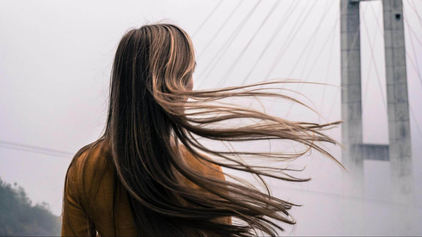 Woman in brown top with hair flying in wind