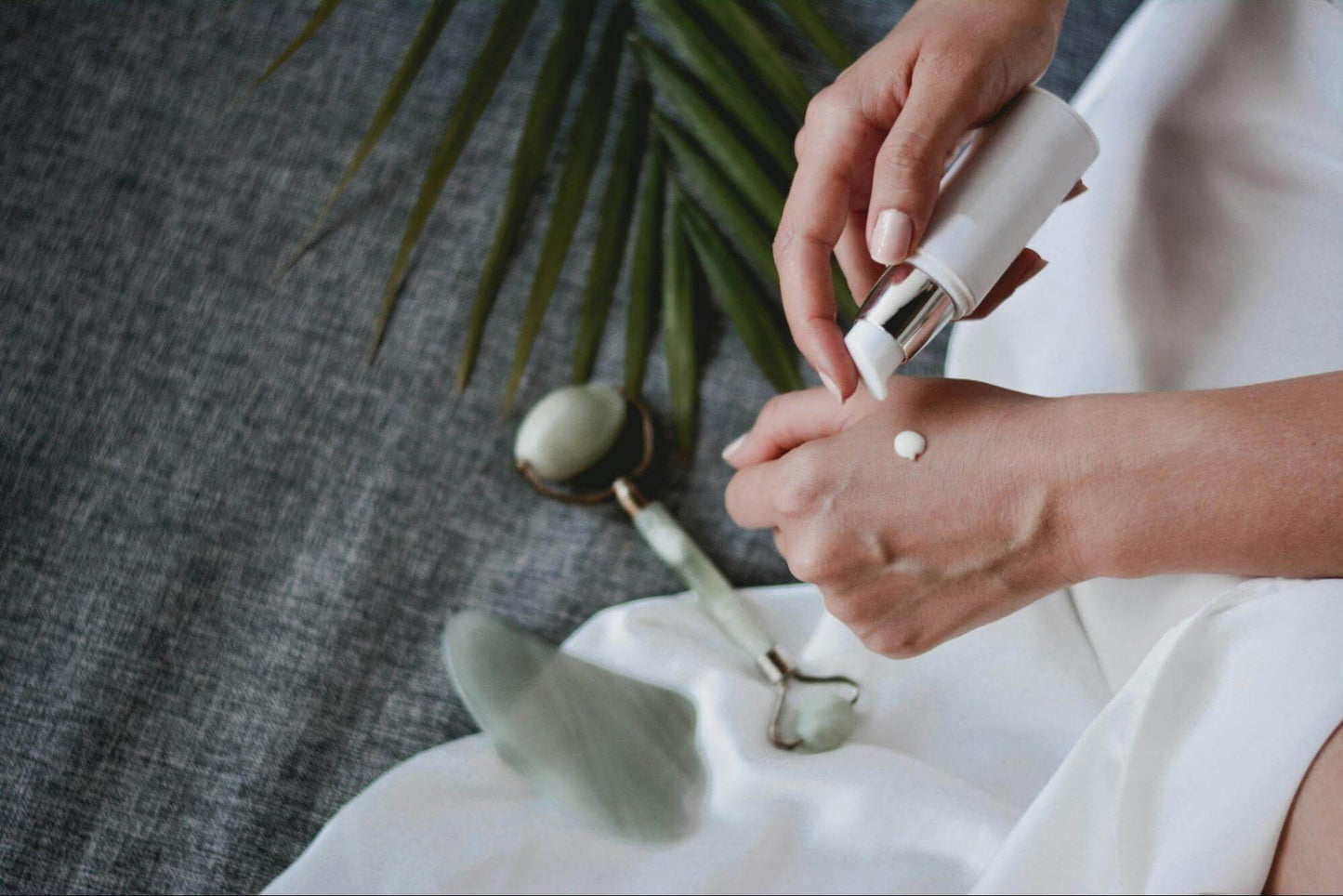 A person applying a small amount of cream onto the back of their hand