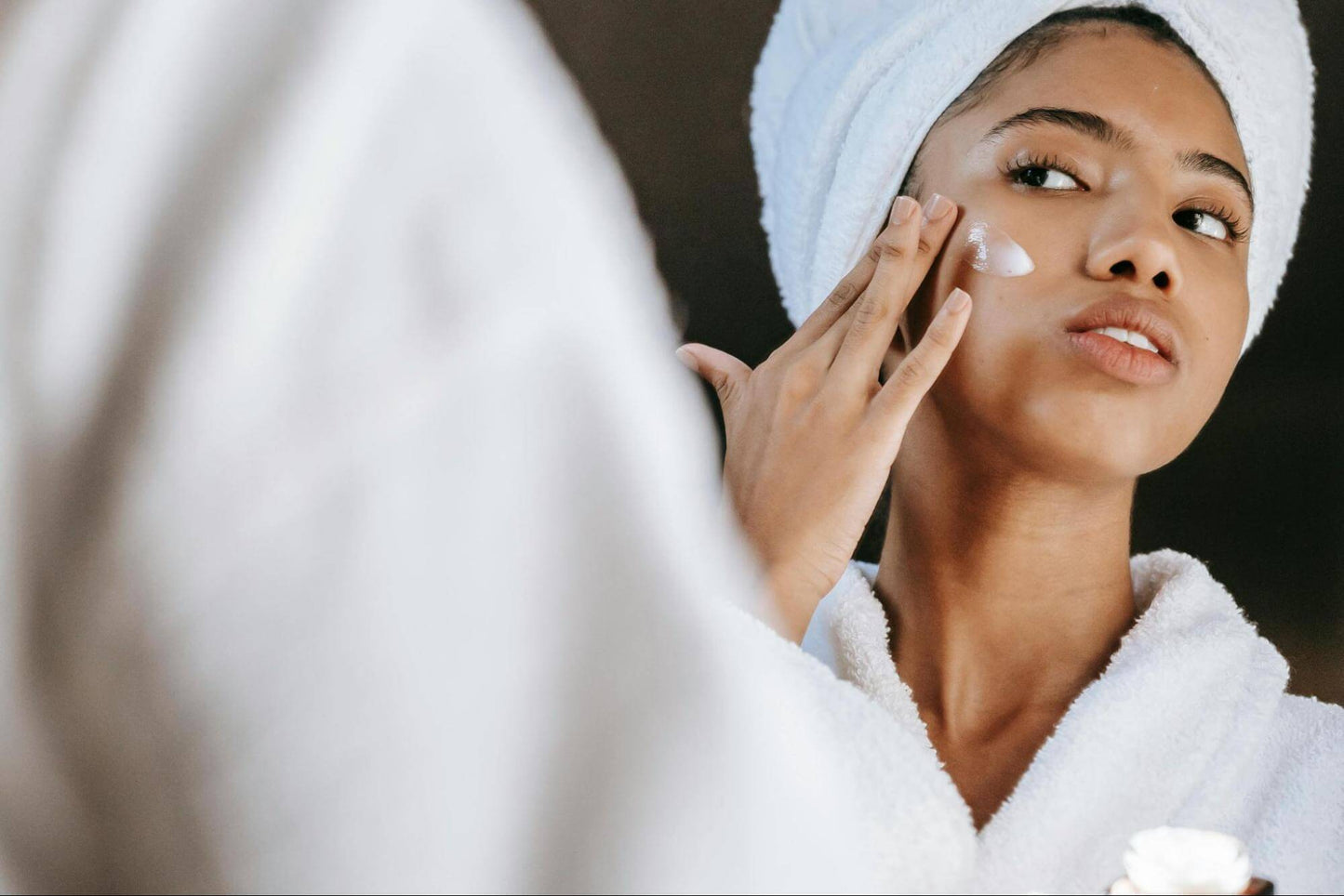 woman applying cream on face in morning