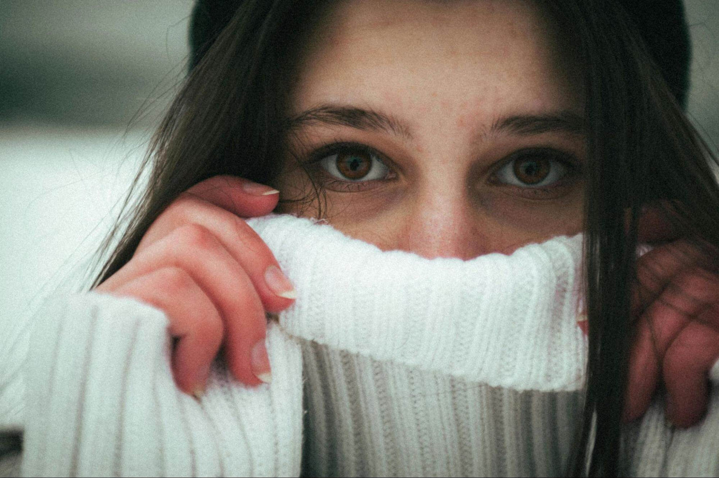 brunette woman pulling neck of sweater over mouth