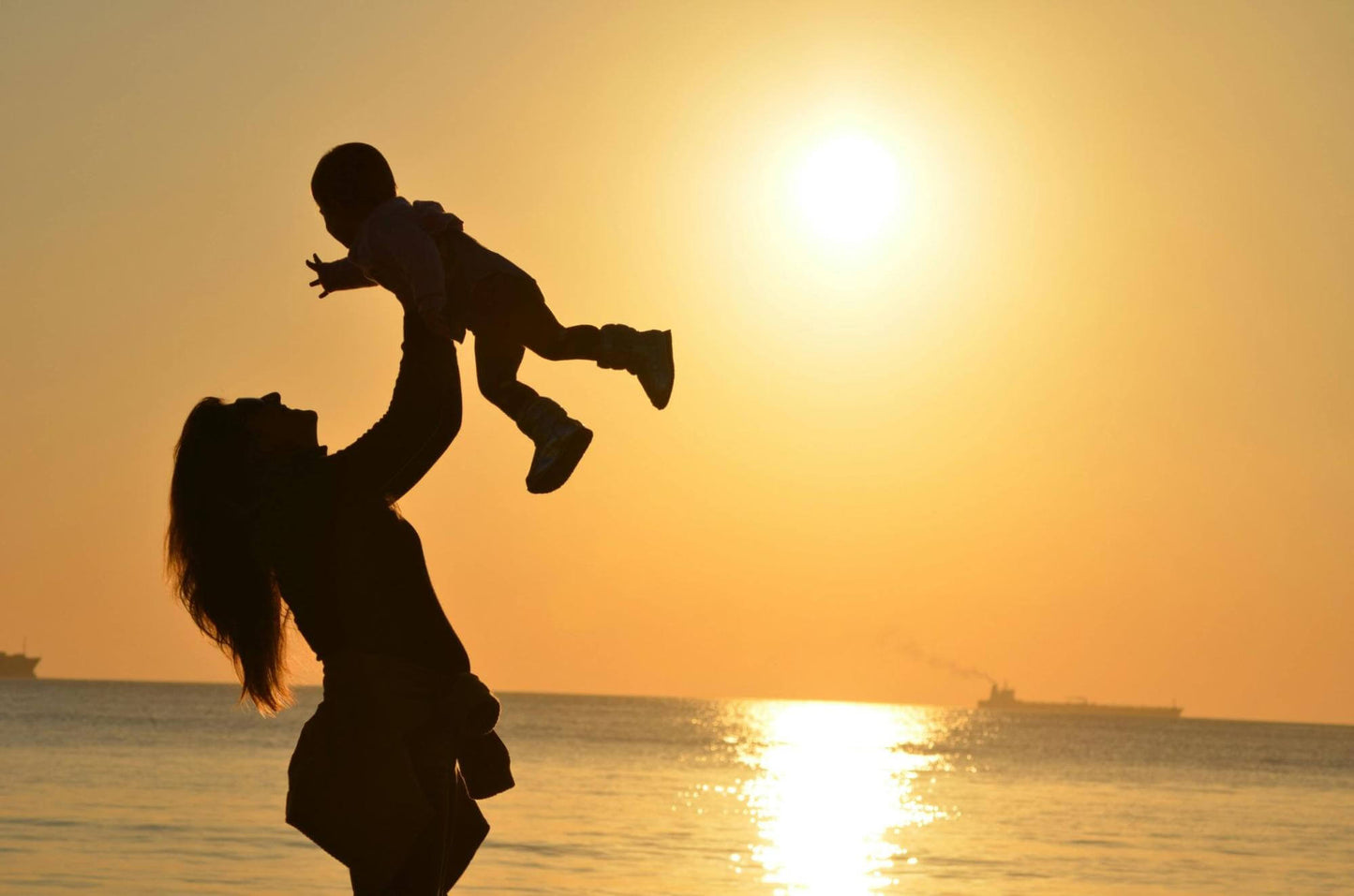 Mother Carrying Her Baby at Beach during Golden Hour